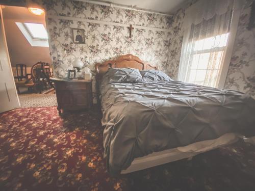 a bedroom with a bed and a table and a window at Lizzie Borden House in Fall River