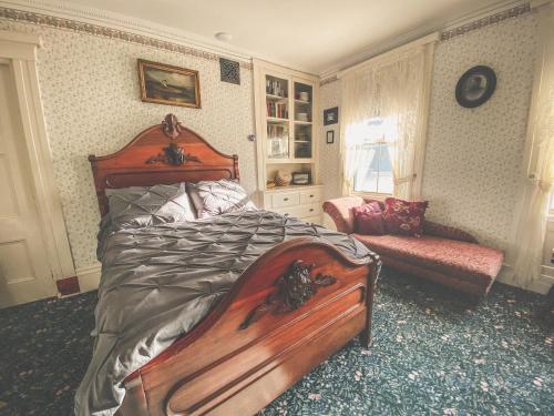 a bedroom with a large wooden bed and a couch at Lizzie Borden House in Fall River