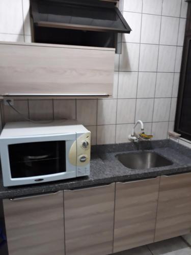un four micro-ondes installé au-dessus d'un comptoir de cuisine dans l'établissement Apartamento Meia Praia Itapema, à Itapema