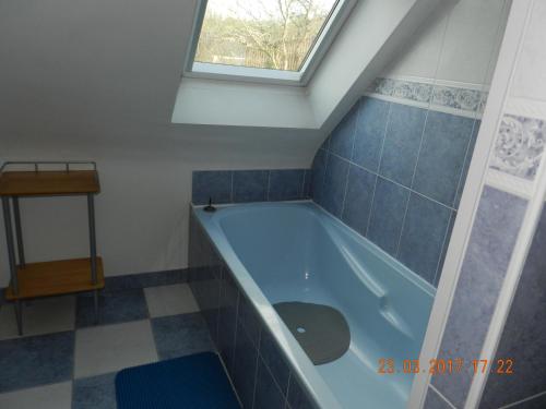 La salle de bains est pourvue d'une baignoire bleue et d'une fenêtre. dans l'établissement Patras, à Ergué-Gabéric