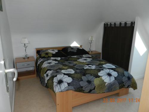 1 dormitorio con 1 cama con colcha de flores en Patras en Ergué-Gabéric