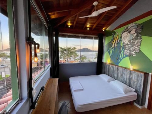 a bedroom with a bed in a room with windows at Green Haven Hostel in Ubatuba