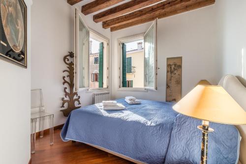 1 Schlafzimmer mit einem blauen Bett und 2 Fenstern in der Unterkunft 7 WINDOWS ON VENICE in Venedig