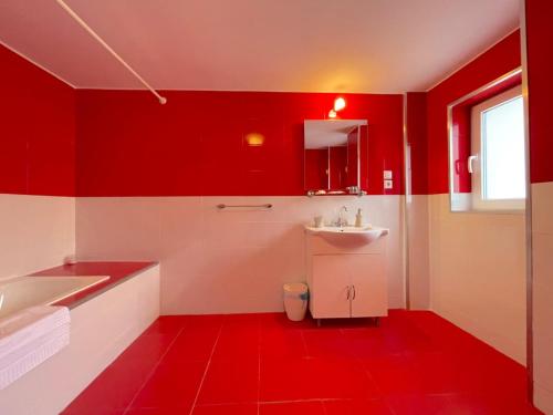 a red and white bathroom with a sink and a tub at Livada Studio Apartments in Braşov