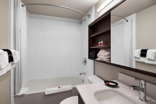 a white bathroom with a sink and a tub at Microtel Inn & Suites by Wyndham Antigonish in Antigonish