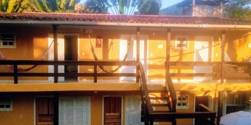 a balcony of a yellow building with a ladder at SUITES E CHALES PRIVADOS Rock's&Rose's home in Camburi