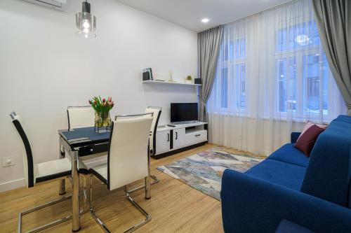 ein Wohnzimmer mit einem Tisch und einem blauen Sofa in der Unterkunft Moder Chic Apartment in Center-PRIME RENTALS in Kaunas