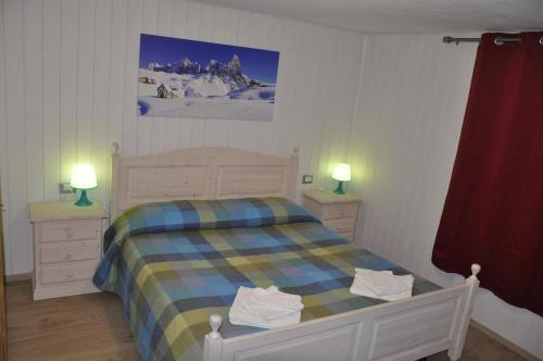 una camera con un letto con due cassettiere e due lampade di Casa Tania a Pozza di Fassa