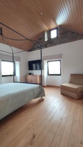 a bedroom with a bed and a couch and windows at Pomar das Oliveiras - Private Swimming pool - Free EV Chrg - Pet Friendly in Carvalhal Cimeiro