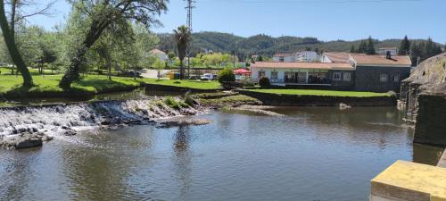 a river with a waterfall in front of a house at Pomar das Oliveiras - Private Swimming pool - Free EV Chrg - Pet Friendly in Carvalhal Cimeiro