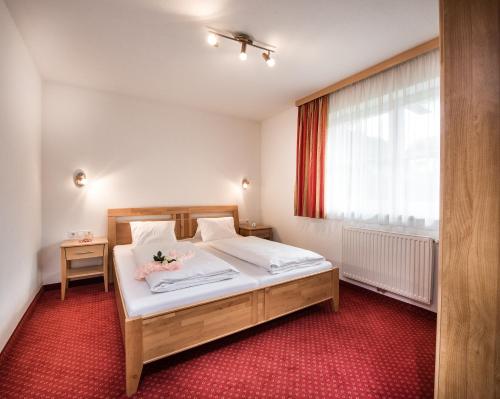 Schlafzimmer mit einem Bett und einem roten Teppich in der Unterkunft Appartements Salzburgerhof in Flachau