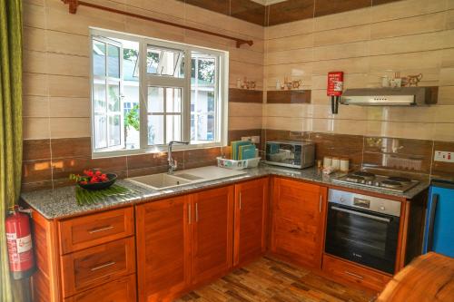 eine Küche mit Holzschränken, einem Waschbecken und einem Fenster in der Unterkunft Villa Charette-Self Catering Villas in La Digue