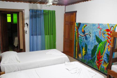 a room with two beds and a painting on the wall at Hotel La Cascada in Puntarenas