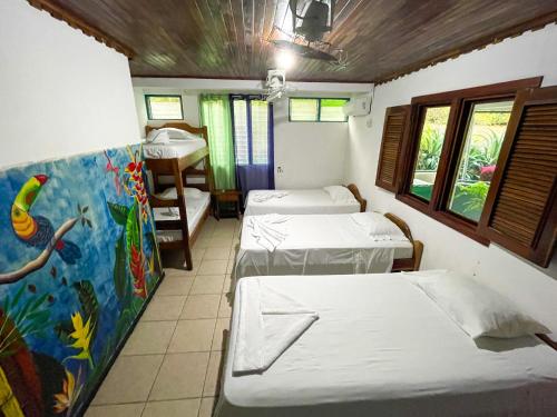 a room with three beds and a painting on the wall at Hotel La Cascada in Puntarenas