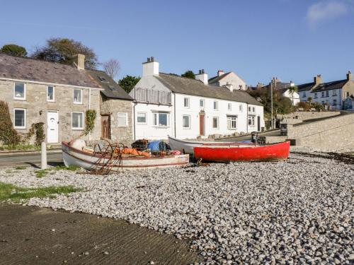 two boats sitting on a rocky beach next to houses at 14 Parc Delfryn in Brynteg