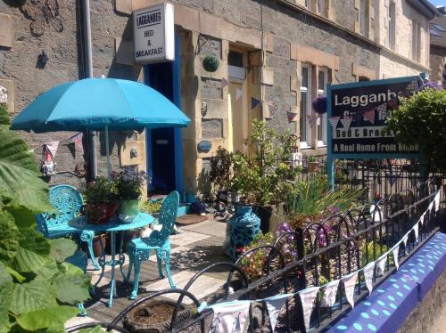 a table and chairs with an umbrella and plants at Lagganbeg Guest House in Oban