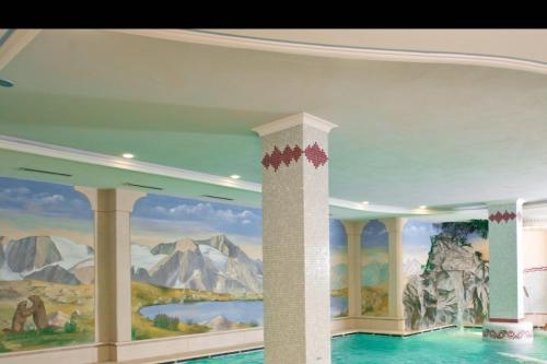 Una habitación con una pintura de montañas en el techo. en Residence Hotel 4s Montagna, en Cogolo