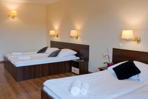 two beds in a hotel room with white sheets at Pensjonat pod Samowarem in Tylicz