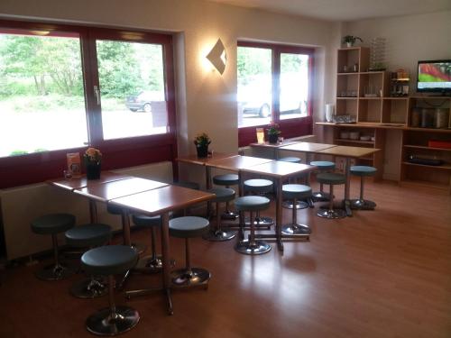 a classroom with tables and stools in a room with windows at Motel 24h Hannover in Hannover
