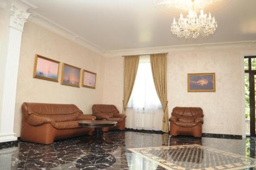 a living room with leather furniture and a chandelier at VLG Hotel in Boryspilʼ