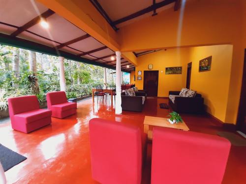 a living room with red chairs and a table at Palitha Homestay in Sigiriya
