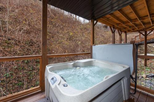 une grande baignoire installée sur une terrasse couverte dans l'établissement Night Owl cabin, à Gatlinburg