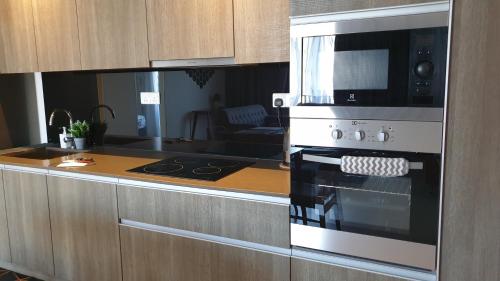 a kitchen with a stove and a microwave at TESS - By The Sea, Batu Ferringhi Penang in Batu Ferringhi