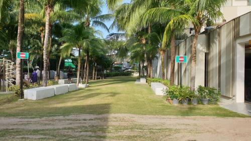 a park with palm trees next to a building at TESS - By The Sea, Batu Ferringhi Penang in Batu Ferringhi