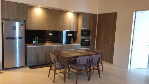 a kitchen with a table and a stainless steel refrigerator at TESS - By The Sea, Batu Ferringhi Penang in Batu Ferringhi