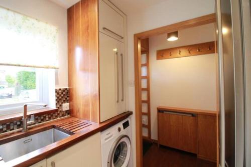 a kitchen with a washing machine and a sink at Cheerful Two-Bedroom Residential Home in Oxford