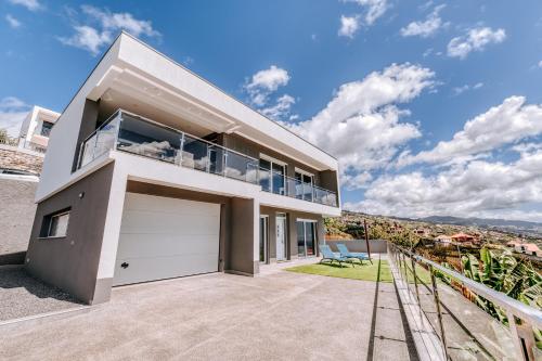 a house with a balcony and a garage at Casa das Voltinhas in Ponta do Sol