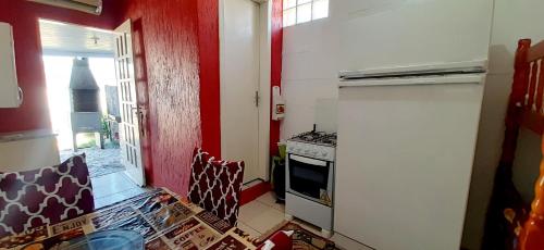 cocina con nevera blanca y pared roja en KITNET k3 em TORRES-RS - Na mais bela praia Gaúcha - Cozinha - Banheiro - Ar condicionado - TV - Wi-Fi - Estacionamento - Acomoda até 6 pessoas - Anfitriã SuperHost no BNB, en Torres
