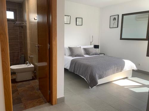 1 dormitorio con 1 cama y baño con lavamanos en Sea views modern villa for relaxing holidays en Costa Teguise
