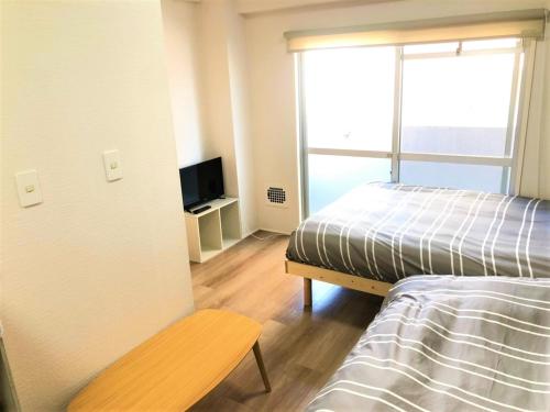 una camera con letto, TV e finestra di Hotel PEACE PARK Tokaichi - Vacation STAY 95320v a Hiroshima