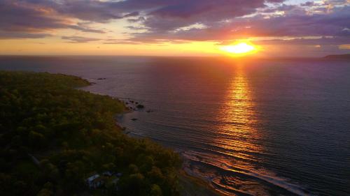 an aerial view of the sun setting over the ocean at Pavones Point in Pavones