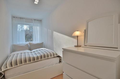 een witte slaapkamer met een bed en een raam bij Domizil Strandallee 30 Domizil Strandallee 30 Appartement 28 in Timmendorfer Strand