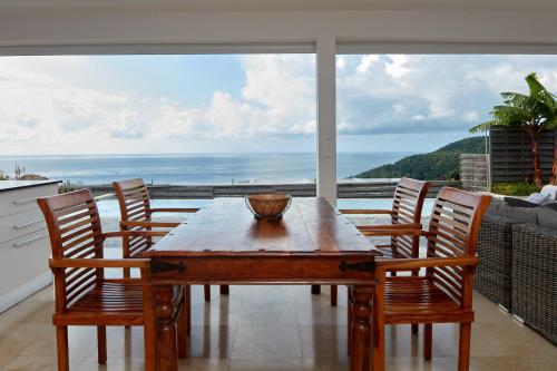 a wooden table with chairs and a view of the ocean at Savane Paille in Deshaies