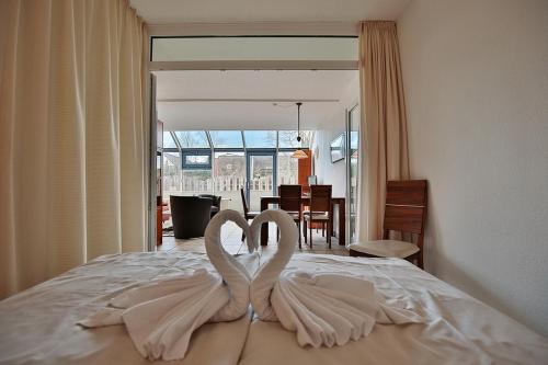 Zwei weiße Schwäne sitzen auf einem Bett in der Unterkunft Strandhotel - Niendorf Strandhotel Niendorf Appartement 48 in Niendorf