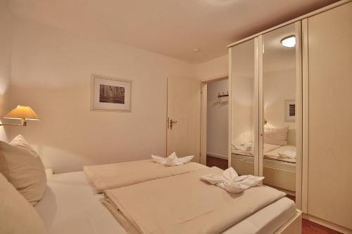 1 Schlafzimmer mit 2 Betten und einem Spiegel in der Unterkunft Gorch-Fock-Park Haus 02 Gorch Fock Park 2 Appartement 02 in Timmendorfer Strand