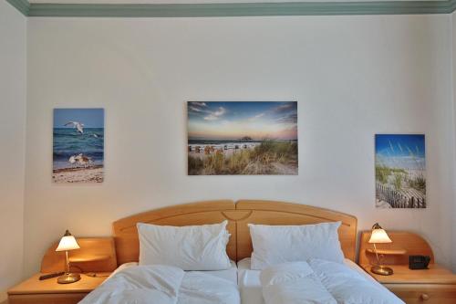 een slaapkamer met twee bedden en drie foto's aan de muur bij Domizil Strandallee 30 Domizil Strandallee 30 Appartement 06 in Timmendorfer Strand