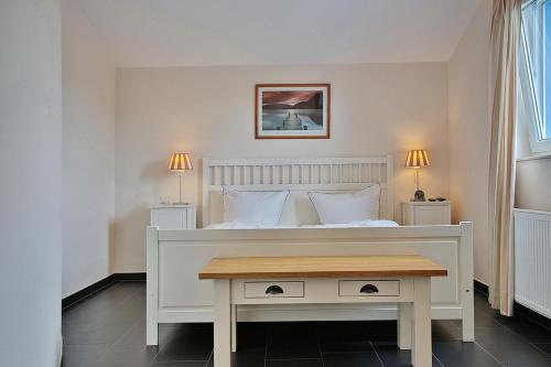 een slaapkamer met een wit bed en een houten tafel bij Penthouse am Platz Penthouse am Platz Appartement 10 in Timmendorfer Strand