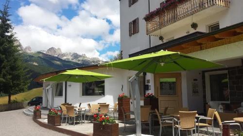 a patio with chairs and umbrellas in front of a building at Ciasa Alpina Relax Hotel in Moena