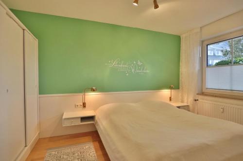 een slaapkamer met een bed en een groene muur bij Haus Windrose Windrose Appartement 3 in Scharbeutz