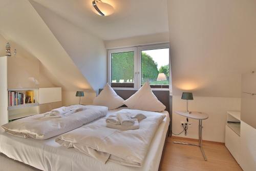 a bedroom with two beds with white sheets and a window at Haus am Seehof Seemöwe Appartement 4 in Sierksdorf