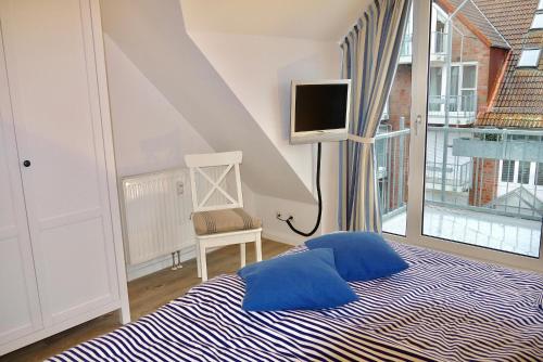 a bedroom with a bed with blue pillows and a tv at Strandduene Stranddüne Appartement 12 in Haffkrug