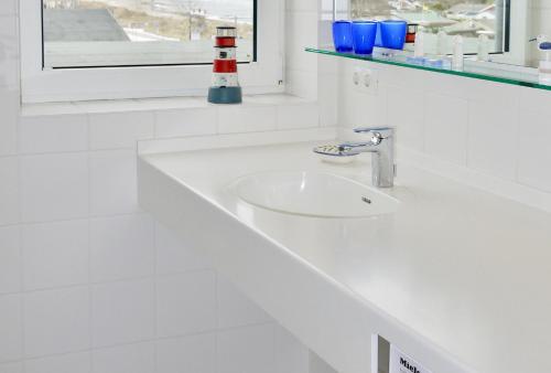 a white sink in a white bathroom with a window at Strandduene Stranddüne Appartement 12 in Haffkrug