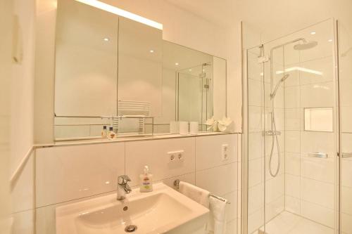 La salle de bains blanche est pourvue d'un lavabo et d'une douche. dans l'établissement Villa Seeperle II Villa Seeperle II Herzmuschel Appartement 18, à Scharbeutz