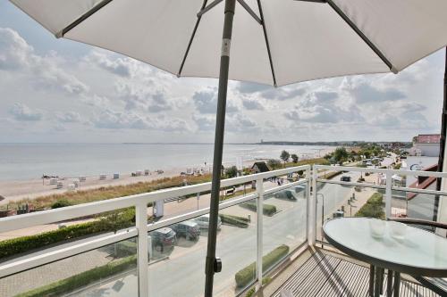 a balcony with an umbrella and a view of the beach at Stranddomizil Stranddomizil Appartement 13 in Haffkrug