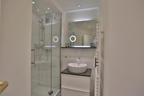 une salle de bain avec un lavabo et une douche avec un miroir dans l'établissement Residenz Ostseestrand Appartement 10, à Scharbeutz