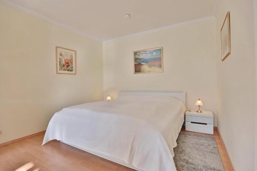 ein weißes Schlafzimmer mit einem weißen Bett und zwei Lampen in der Unterkunft Hanseat am Hang 3 - 5 Hanseat Appartement 21 in Scharbeutz